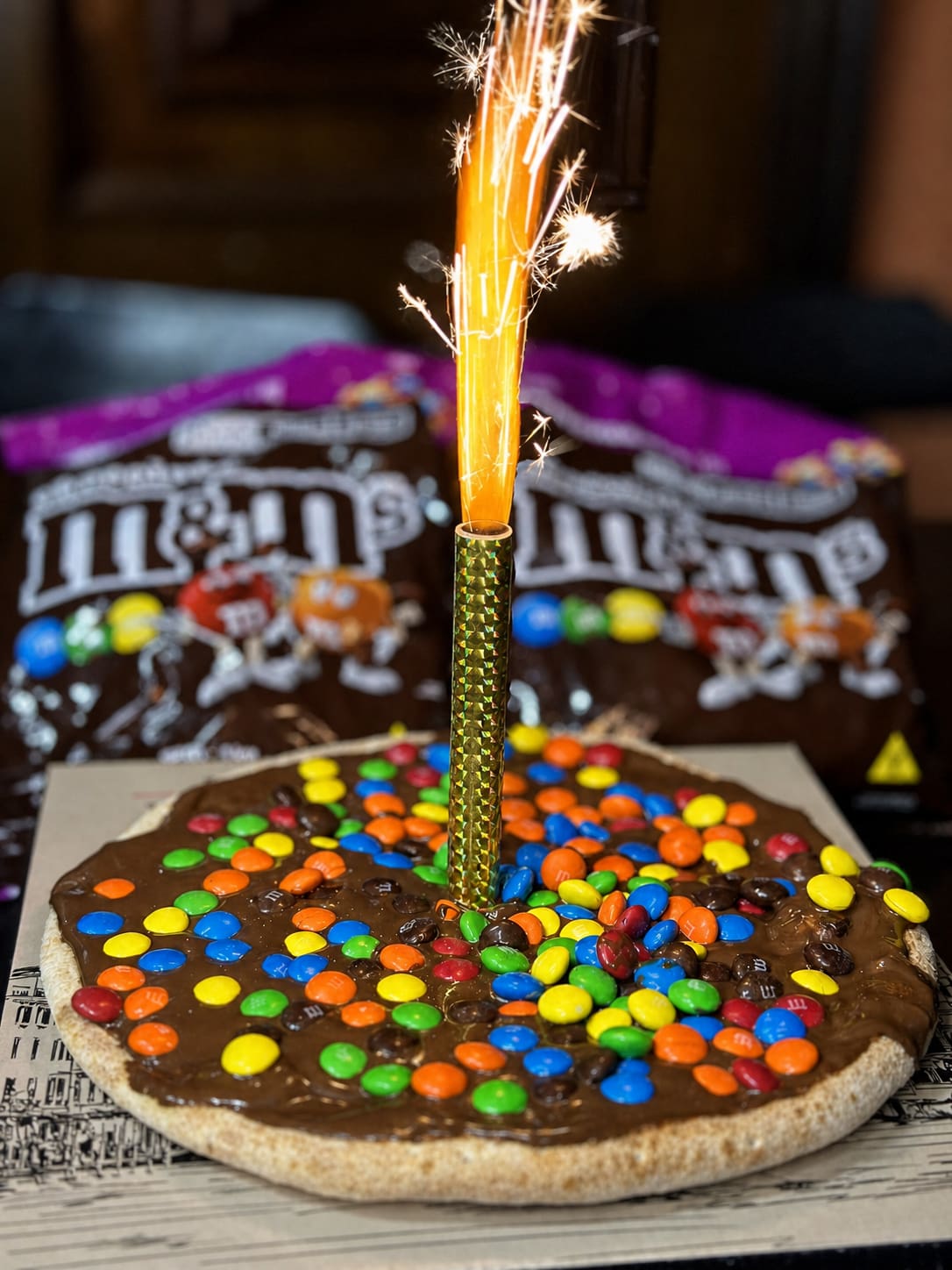 Pizza doce de chocolate com confeitos coloridos e vela de aniversário na Italiamo Capicche