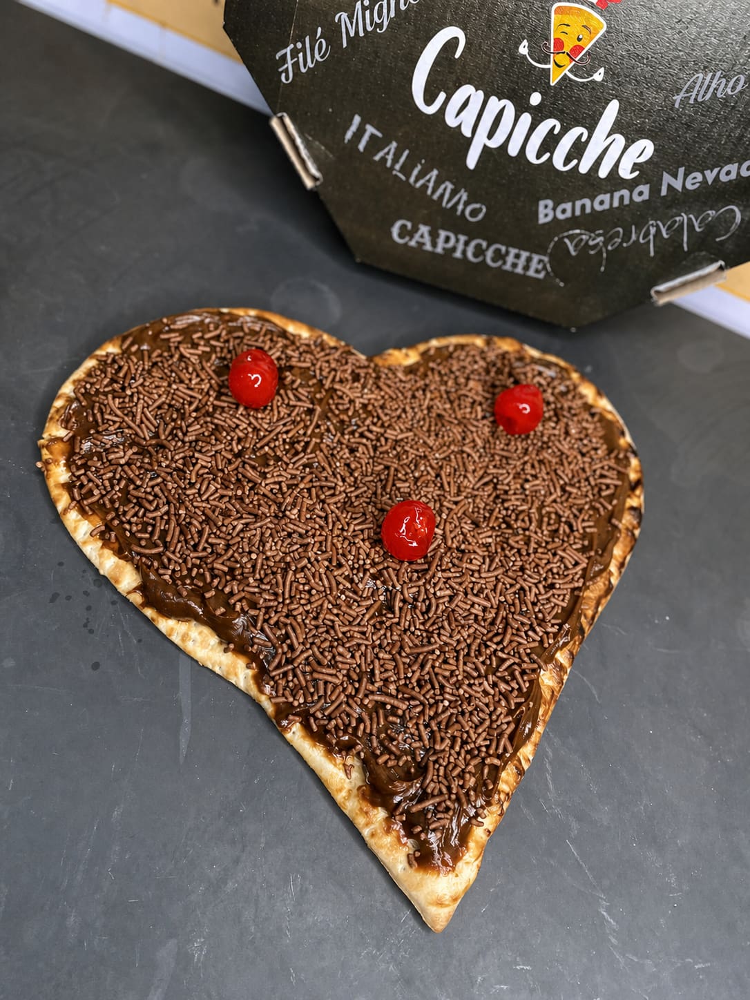 Pizza doce em formato de coração com chocolate e cerejas